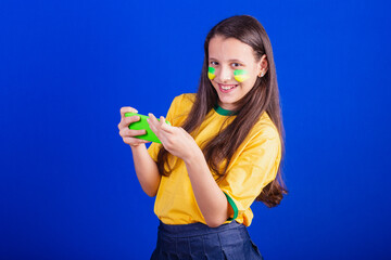 young girl, soccer fan from Brazil. holding cellphone, watching game, cheering for Smartphone....