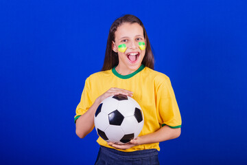 young girl, soccer fan from Brazil. holding soccer ball.
