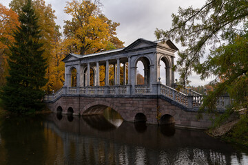 Fototapeta na wymiar Marble bridge on the shore of a Large pond in the Catherine Park in Tsarskoye Selo on an autumn day, Pushkin, St. Petersburg, Russia