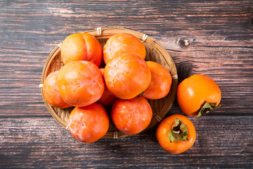 Ripe persimmon or kaki fruit on wooden table.