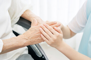 高齢者女性の手を握る介護士の手元