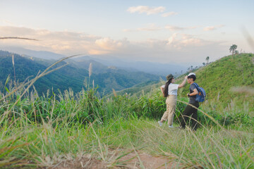 Fototapeta premium Happy young couple watching the sunset in the mountains at Mae Wong National Park, Kamphaeng Phet, Thailand
