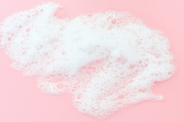 Smear of cleansing facial foam close-up on a pink background top view.