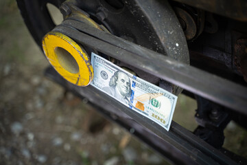 Hundred dollar bill close-up on an industrial background. Money on a belt driven tractor engine...