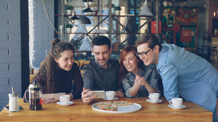 Young people are having funny video chat holding smartphone looking at webcam chatting to friend at...