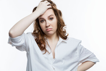 Tired young woman in a white shirt holds her head. Women's problems, depression and illness. White background.