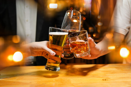 food and drink male friends are happy drinking beer and clinking glasses at a bar or pub.