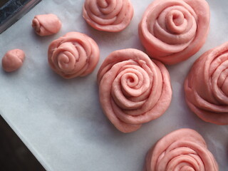 Top view pink rose shaped bread bun on white baking paper