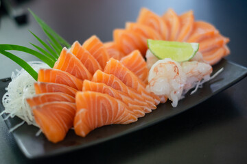 Salmon Sashimi in Japanese buffet restaurant menu.  Fresh salmon fillet on black plate salmon slices. Salmon sashimi. Asian Food Menu. Seafood sashimi.