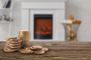 Wooden table with coins and fireplace in room. Concept of heating season
