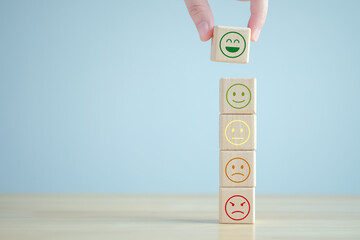 Hand choosing happy face from many emotion on wooden blocks. Positive thinking, Feedback,...