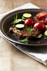 Grilled beef steak with tomatoes and fresh herbs. Copy space.	