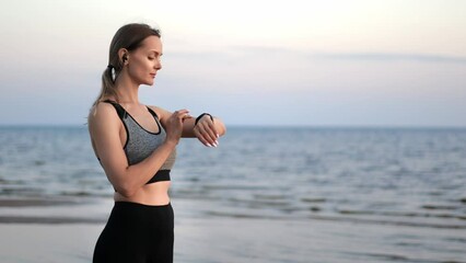 Sports woman checking heart rate on smartwatch enjoy jogging running sunset beach sea waves slowmo - Powered by Adobe