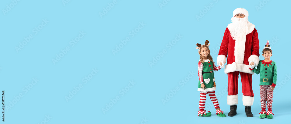 Wall mural cute little elves with santa claus on light blue background with space for text