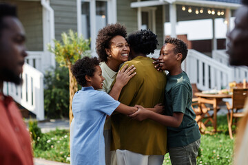 Waist up portrait of African American family embracing while gathering for Summer party outdoors