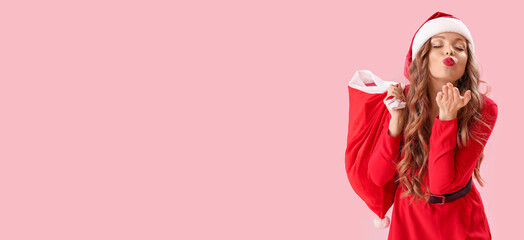 Sexy young woman in Santa costume blowing kiss on pink background with space for text
