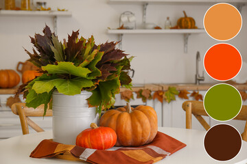 Vase with autumn leaves and fresh pumpkins on table in kitchen. Different color patterns