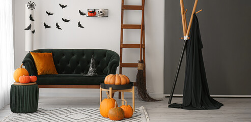 Interior of living room with sofa, ladder and pumpkins decorated for Halloween