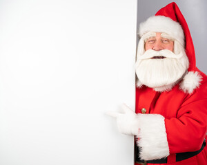 Santa Claus peeks out from behind an ad on a white background. Merry Christmas.