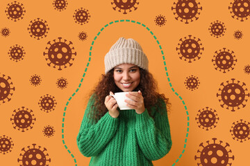 Happy young African-American woman with cup of hot tea and drawn virus on orange background. Concept of strong immunity