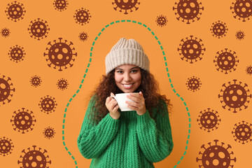 Happy young African-American woman with cup of hot tea and drawn virus on orange background....
