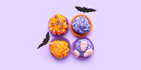 Tasty Halloween cupcakes on lilac background, top view