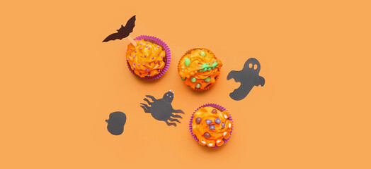 Tasty Halloween cupcakes and decor on orange background, top view