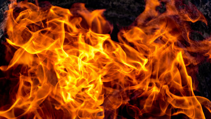 Burning fire close up. Bright orange and red flames on a dark background. Open flame heating. Problems with heating and gas.