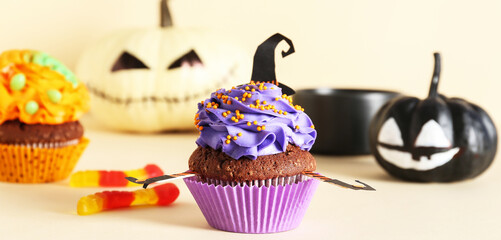 Tasty Halloween cupcake on beige background, closeup