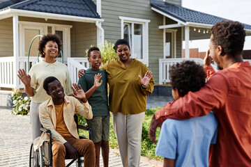Portrait of African American family waving to guests after Summer party