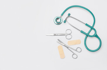 Stethoscope, medical scissors and plasters on white background