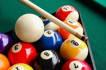 Billiard balls in triangle and cue on table, closeup