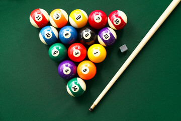 Colorful billiard balls with cue on table