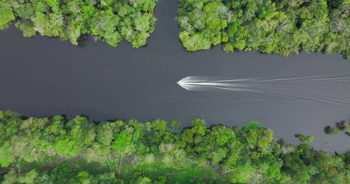 Aerial birdseye dolly left of speedboat navigating waters of Rio Negro, Amazon