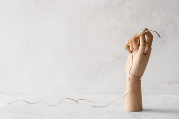 Wooden hand with rope on light background