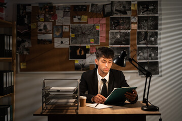 Detective working at desk in his office, investigator on workplace, detective board background