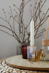 Candle in holder and reed diffuser on table