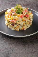 simple salad with crab sticks, eggs, onions and corn dressed with mayonnaise close-up in a plate on the table. vertical