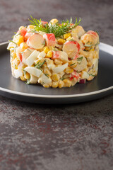 Crab salad with vegetables corn, red onion, hard-boiled eggs and dill closeup in the plate on the table. Vertical