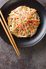 Japanese Kani Salad is a popular side dish with crunchy vegetables and savory crab sticks closeup in the plate on the table. Vertical top view from above