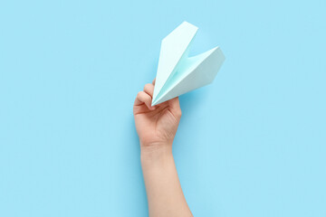 Woman with blue paper plane on color background