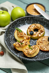 Plate of tasty apple wedges and rounds with nut butter on color wooden table, closeup