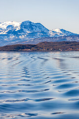 Seascape view with wave pattern and snow capped mountains