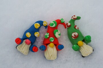 Figures of colorful dwarfs on a background of snow. Christmas decorations. Christmas toys.