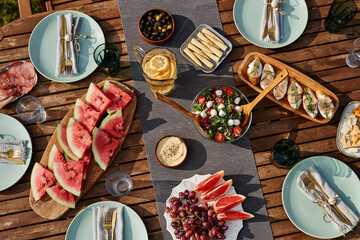 Top view background of wooden dinner table set for Summer party outdoors with fresh fruits and...