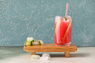 Wooden board with glass of tasty watermelon fresh and ice cubes on color background