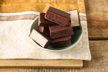 Bowl with tasty bird's milk candies on wooden table