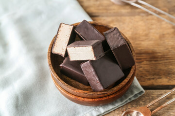 Bowl with tasty bird's milk candies on wooden table