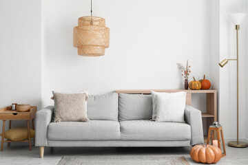 Interior of modern living room with grey sofa and pumpkins