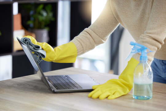 Laptop, cleaning and hands with an office cleaner wiping a computer on a desk or table with sanitizer. Hygiene, disinfectant and rubber gloves with a woman dusting or washing wireless technology